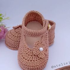 a pair of crocheted baby shoes sitting on top of a table next to flowers