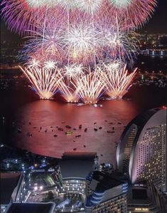 fireworks are lit up over the water and city skylines at night in this aerial photo