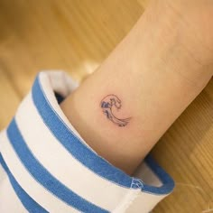 a woman's wrist with a small wave tattoo on the left side of her arm