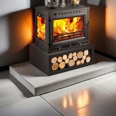 a wood burning stove sitting on top of a white floor next to firewood logs