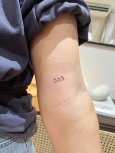 a woman with a small tattoo on her arm that says 55 cents in cursive font