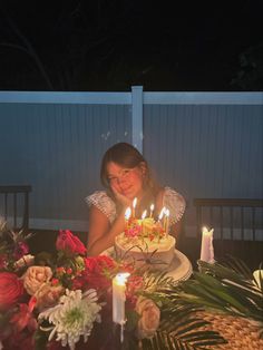 a woman sitting at a table with a cake and lit candles