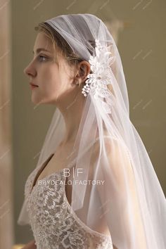 a woman wearing a wedding veil with flowers on the back of her head and hair comb