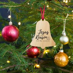 wooden ornament with jesus is the reason on it hanging from a christmas tree