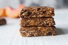 three granola bars stacked on top of each other in front of an orange slice