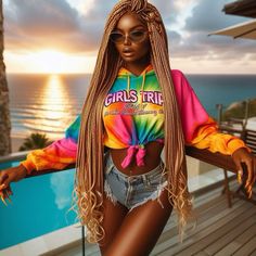 a woman standing next to a swimming pool wearing a tie dye shirt and denim shorts