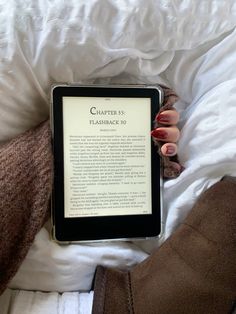 a person laying in bed with their hand on an electronic device that is reading the text