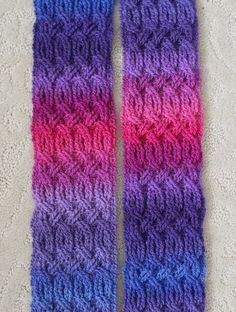 two purple and pink knitted scarfs laying on the floor