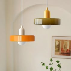 three different colored lights hanging from the ceiling in a living room with white walls and green plants