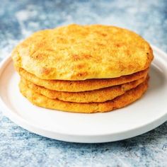 a stack of cornbreads on a white plate sitting on a blue counter top