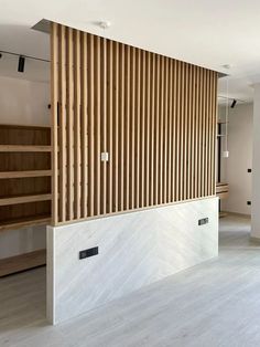 an empty room with wood slats on the wall and white flooring in front of it