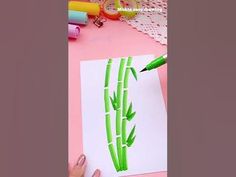 someone is drawing bamboo stalks on paper with colored crayons and markers while they are sitting on a pink surface