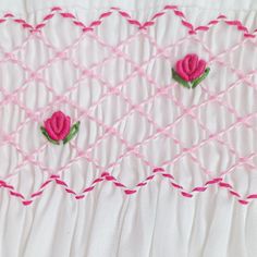 two pink roses are embroidered onto the white fabric, which is being used as an applique