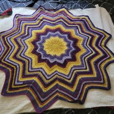 a crocheted blanket is laying on top of a bed