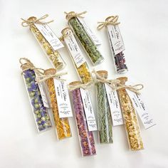 six different types of dried herbs tied together in twine with tags attached to them