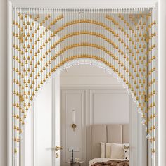 an archway leading into a bedroom with white walls and gold beaded curtains hanging from the ceiling