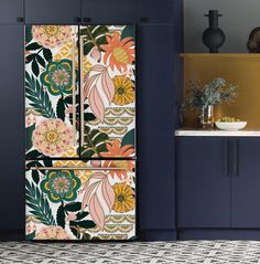 a colorful refrigerator in a kitchen next to a counter with flowers on the front and side