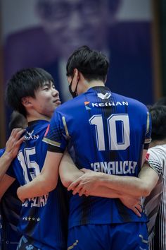 three men in blue uniforms hugging each other