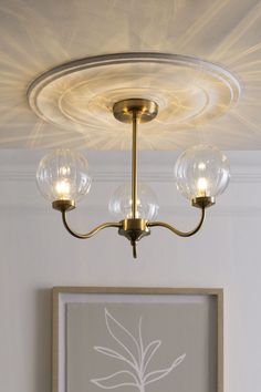 a light fixture with three glass globes hanging from it's center point in a living room