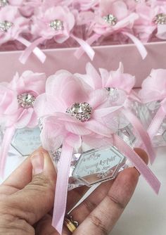 someone is holding a small pink flower in front of some boxes with flowers on them