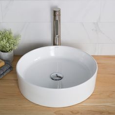 a white sink sitting on top of a wooden counter next to a potted plant