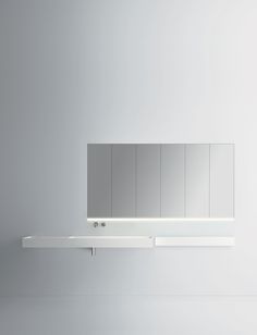 a bathroom mirror sitting on top of a white shelf next to a wall mounted faucet