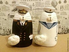 two white cats are dressed up as sailors and sailor cat figurines on a table