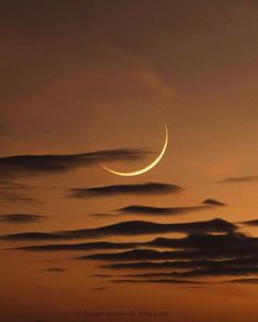 the crescent is seen in the sky at night with clouds around it and an orange glow