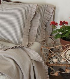 a bed topped with lots of pillows next to a potted plant on top of a table