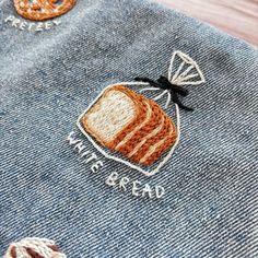 a close up of a piece of bread on a jean jacket with the words eat bread embroidered on it