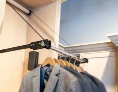 a rack with clothes hanging on it next to a wall mounted coat rack and closet door