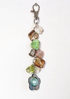 a bunch of different colored stones hanging from a metal hook on a white surface with a keychain attached to it