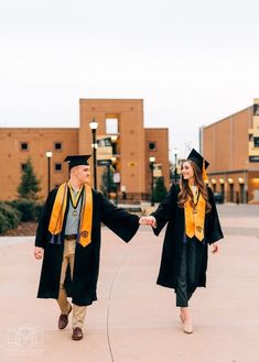 a man and woman in graduation gowns holding hands