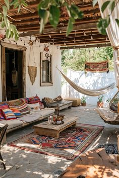 an outdoor living area with hammock, couches and rugs on the ground