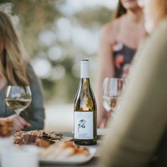 people sitting at a table with wine and food