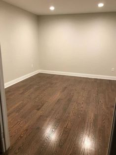 an empty room with hard wood flooring and white paint on the walls is seen in this image