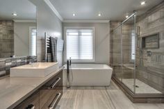 a bathroom with a tub, sink and large mirror