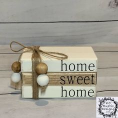 a wooden block with some balls tied to it and the words home sweet home on it