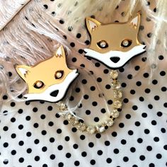 two fox brooches sitting on top of a white and black polka dot blanket