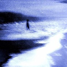 a blurry photo of a person walking on the beach in front of an ocean