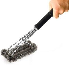 a hand holding a metal brush on top of a white surface