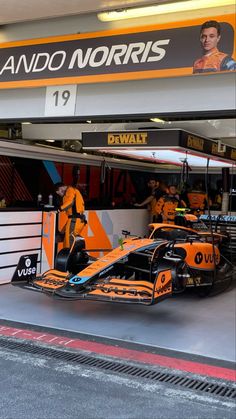 an orange race car parked in front of a garage