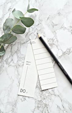 a notepad with a pencil on top of it next to a plant