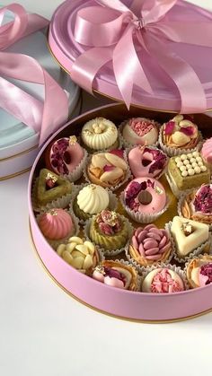 a pink box filled with lots of different types of cupcakes and pastries