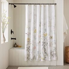 a bathroom with a shower curtain that has flowers on it, and a rug in front of the bathtub