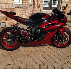 a red and black motorcycle parked in front of a brick building