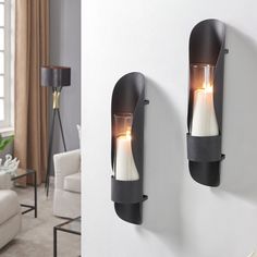 two black sconces with white candles on them