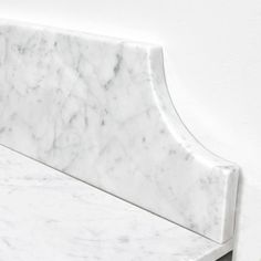 a white marble bench sitting next to a wall