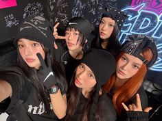 the girls are posing in front of a blackboard with writing on it and wearing beanies