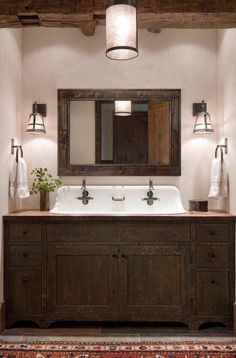 a bathroom with a sink, mirror and two lights on the wall above it's counter